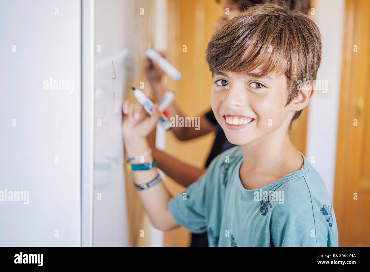 Portrait von lächelnden Jungen mit einem Freund Zeichnung auf einem Whiteboard Stockfoto