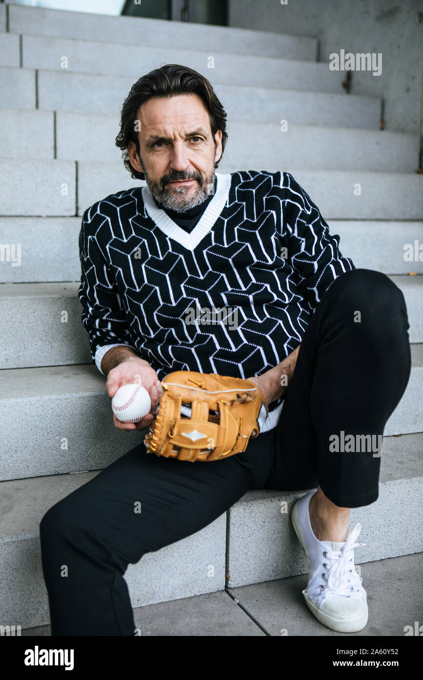 Portrait von modischen reifer Mann sitzt auf der Treppe mit Baseball Catcher und Kugel Stockfoto