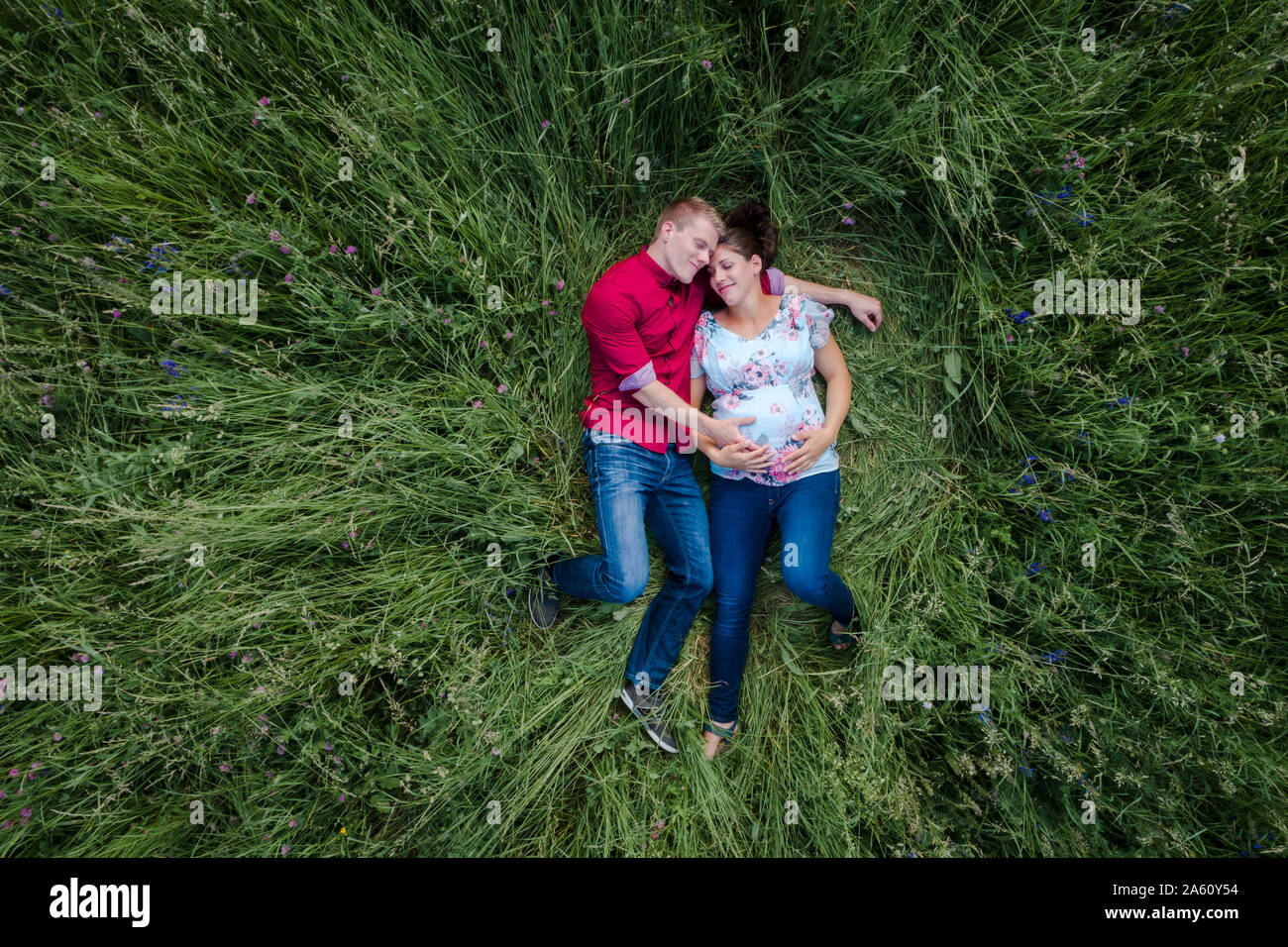 Schwangere Frau und Mann baby Holding Bauch, liegend auf der Wiese Stockfoto