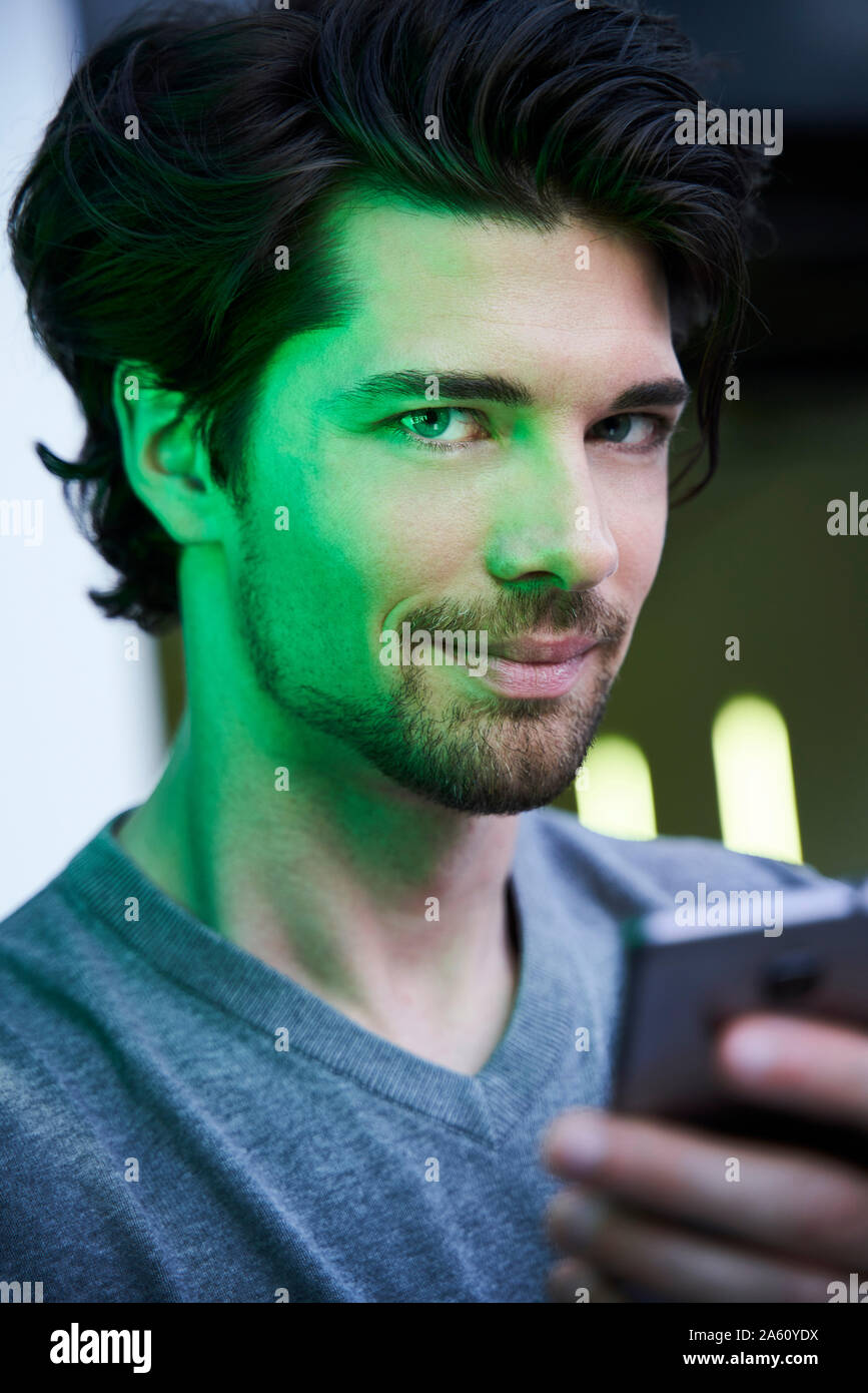 Nahaufnahme der überzeugten Mann in grünes Licht holding Handy Stockfoto