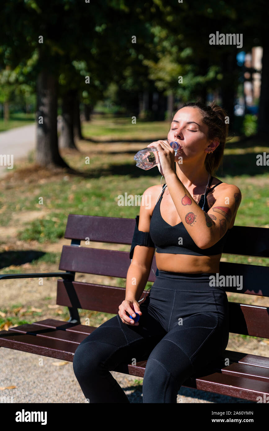 Sportliche junge Frau mit einem kühlen Pause auf der Parkbank Stockfoto