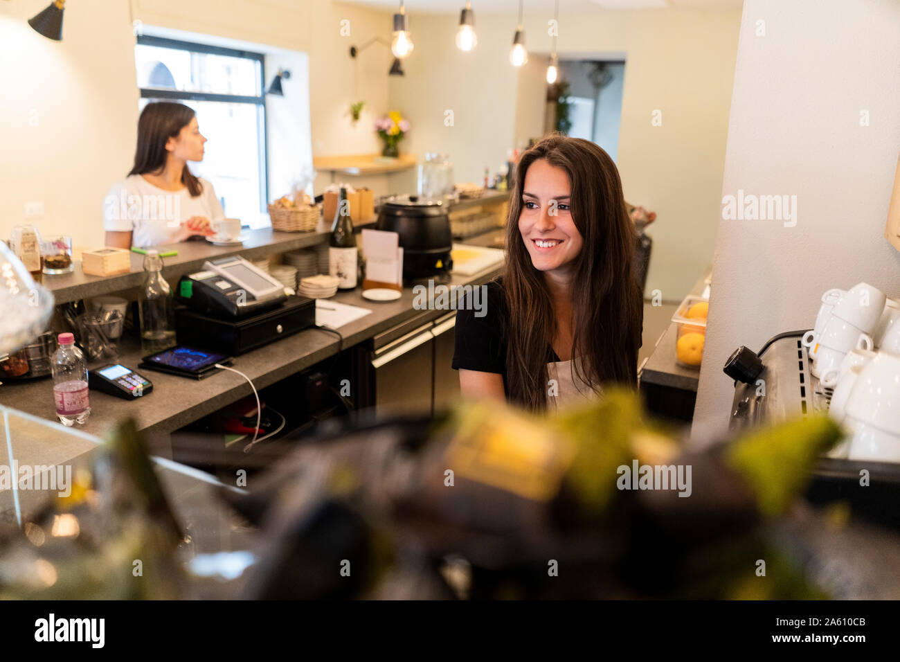 Lächelnde junge Frau hinter der Theke in einem Cafe Stockfoto