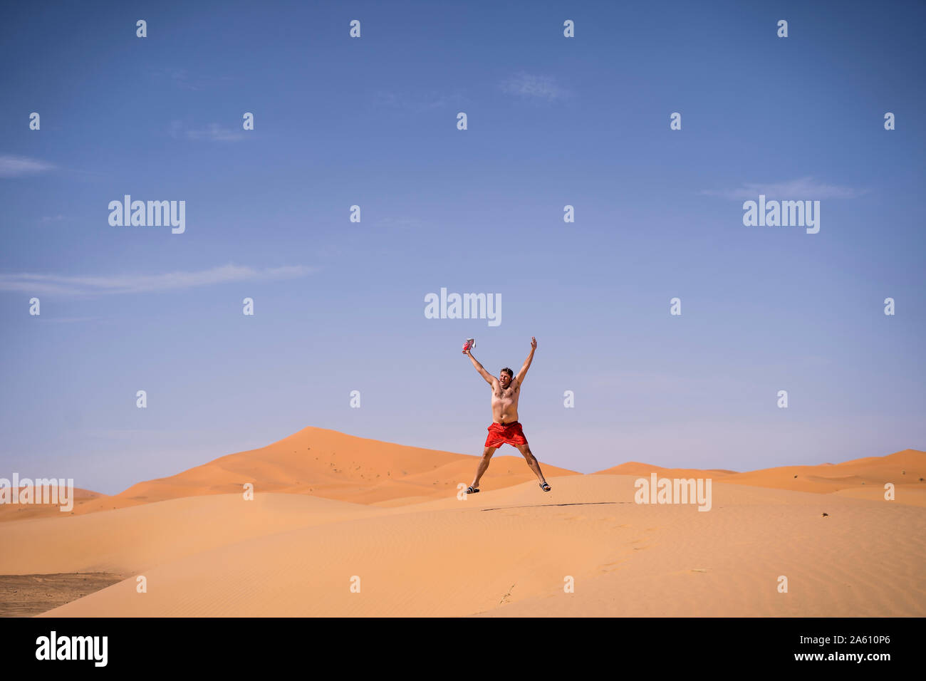 Übergewicht Mann mit Badeshorts in der Wüste von Marokko springen Stockfoto