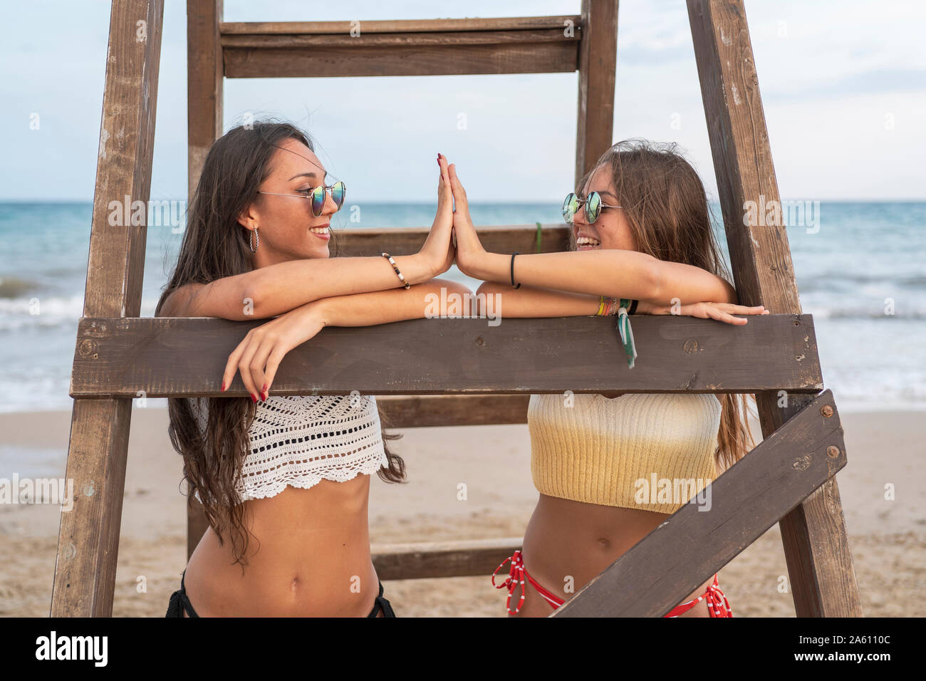 Zwei glückliche weibliche Freunde hohe FIVING auf einer Holzleiter am Strand Stockfoto