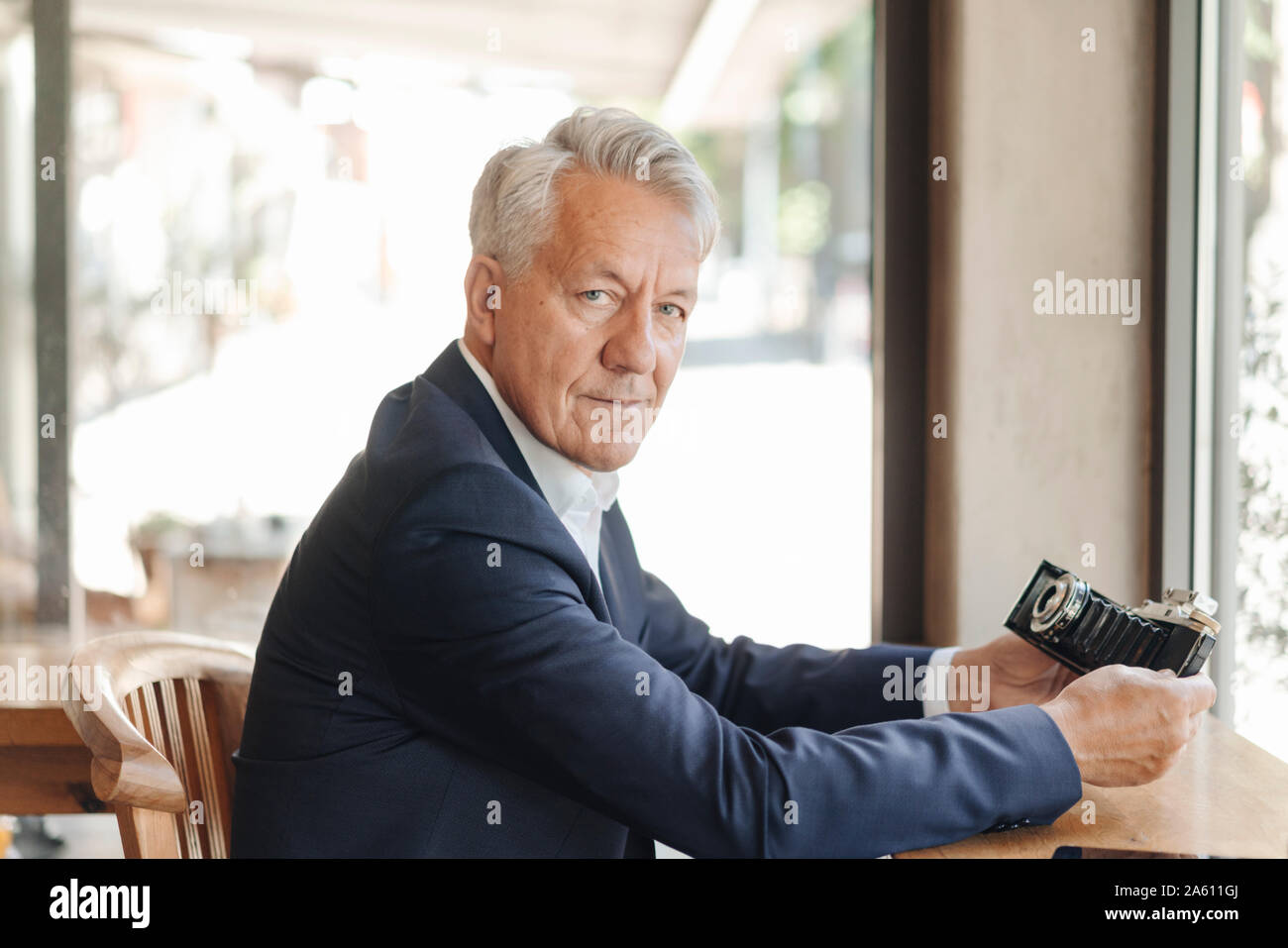 Portrait von älteren Geschäftsmann Holding altmodische Kamera in einem Cafe Stockfoto