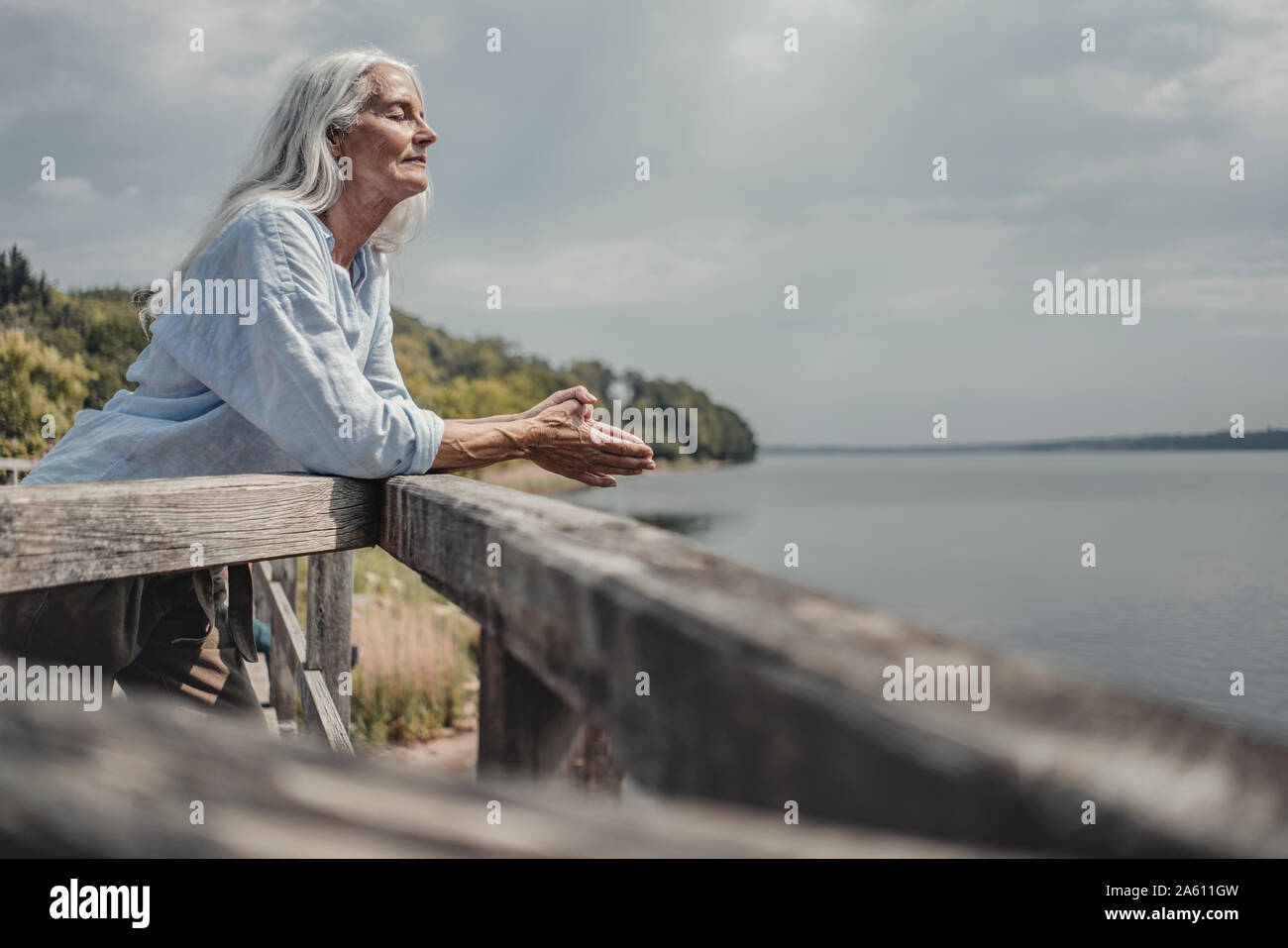 Ältere Frau, die auf der Brücke, entspannende mit geschlossenen Augen Stockfoto