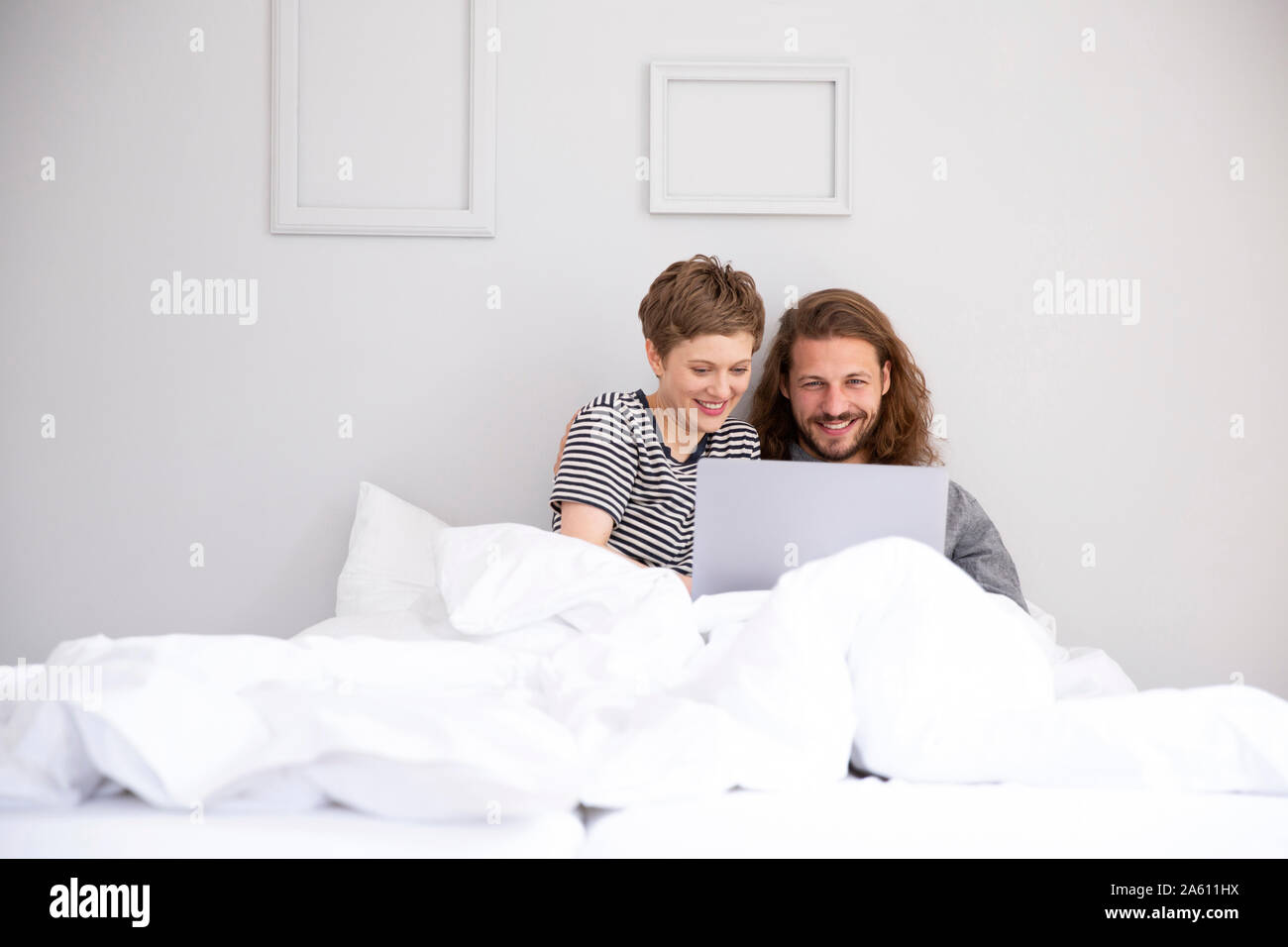 Junges Paar mit Laptop im Bett zu Hause Stockfoto