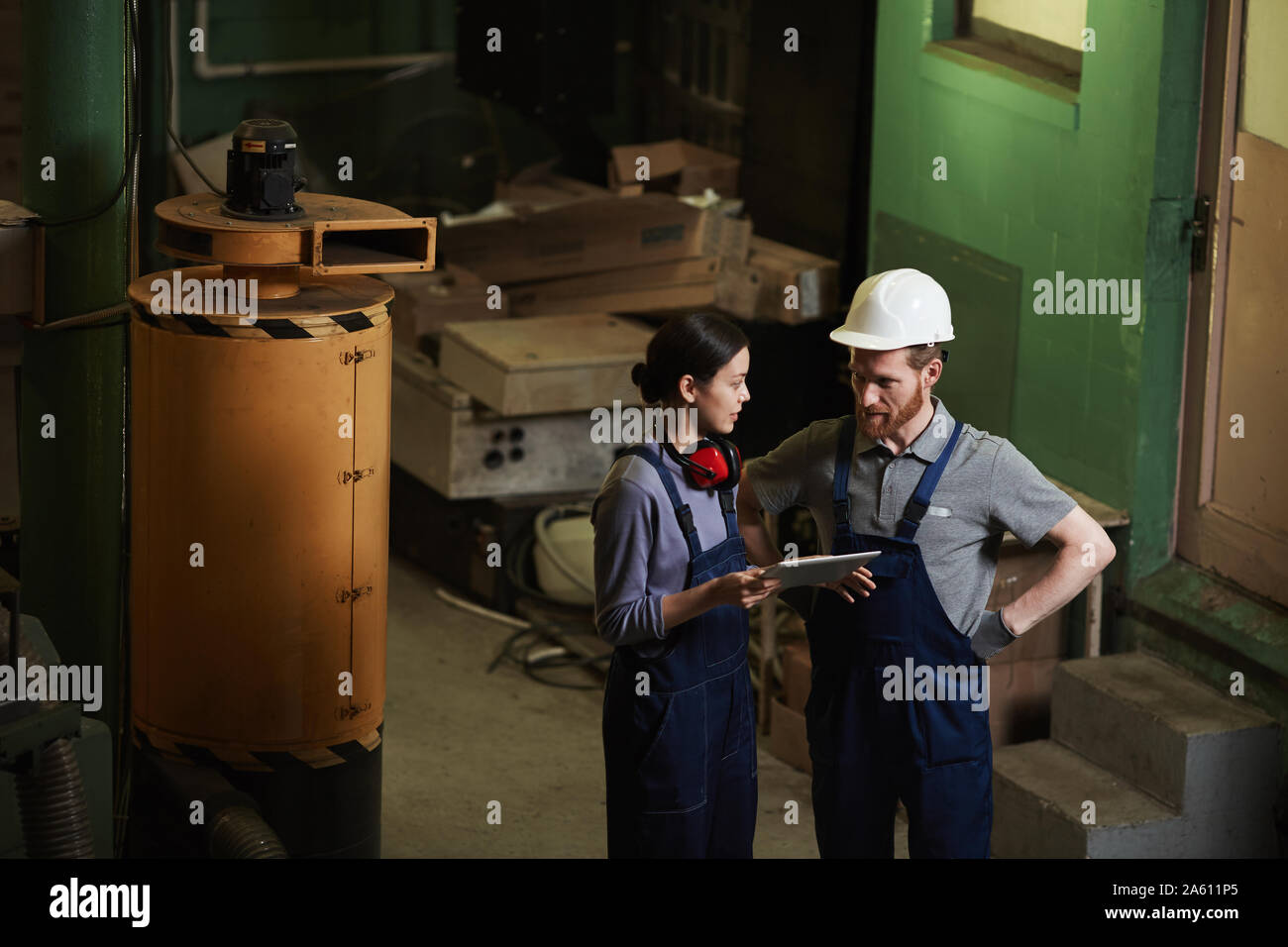 Zwei Arbeiter mit digitalen tablet Arbeit tragen und miteinander zu reden, während man in der Anlage Stockfoto