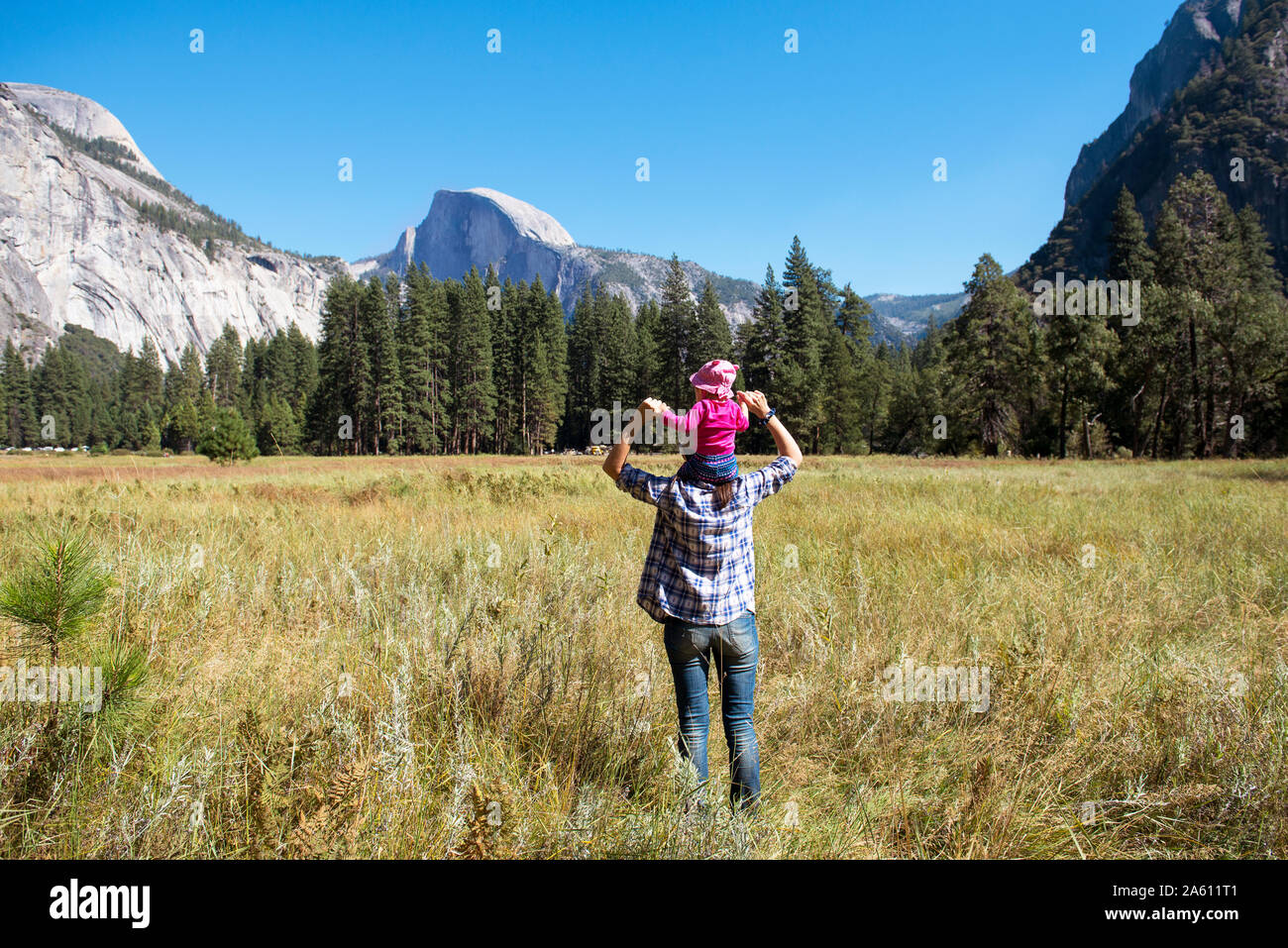 Rückansicht der Vater die kleine Tochter auf seinen Schultern, Yosemite National Park, Kalifornien, USA Stockfoto