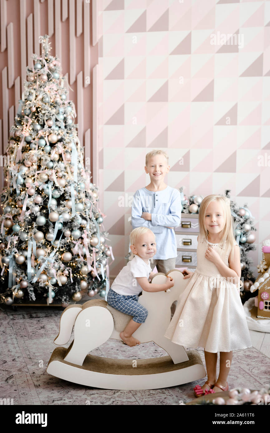 Gruppenbild der drei Kinder vor Weihnachtsbaum Stockfoto