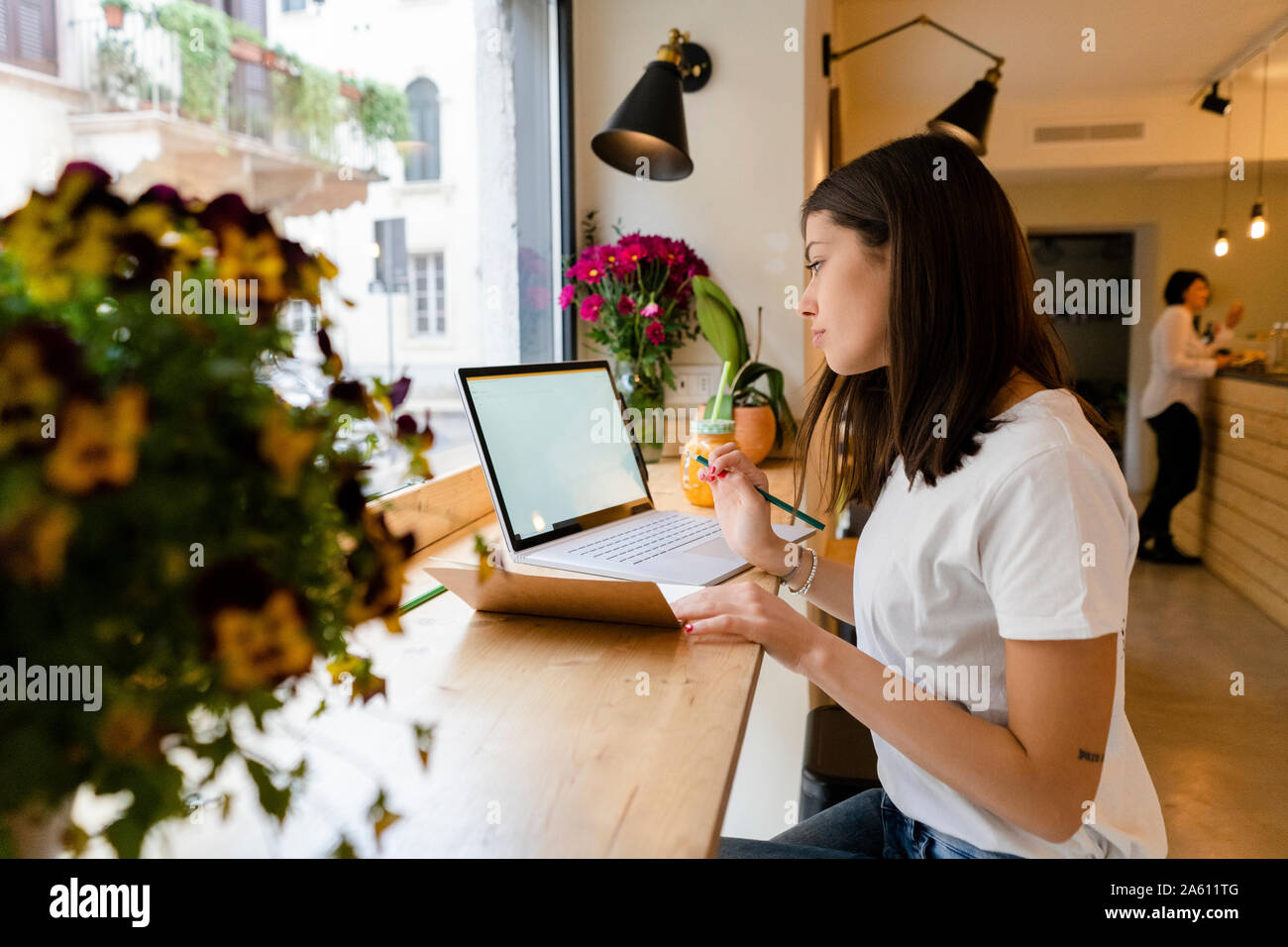 Junge Frau mit Laptop und Notizen in einem Cafe Stockfoto