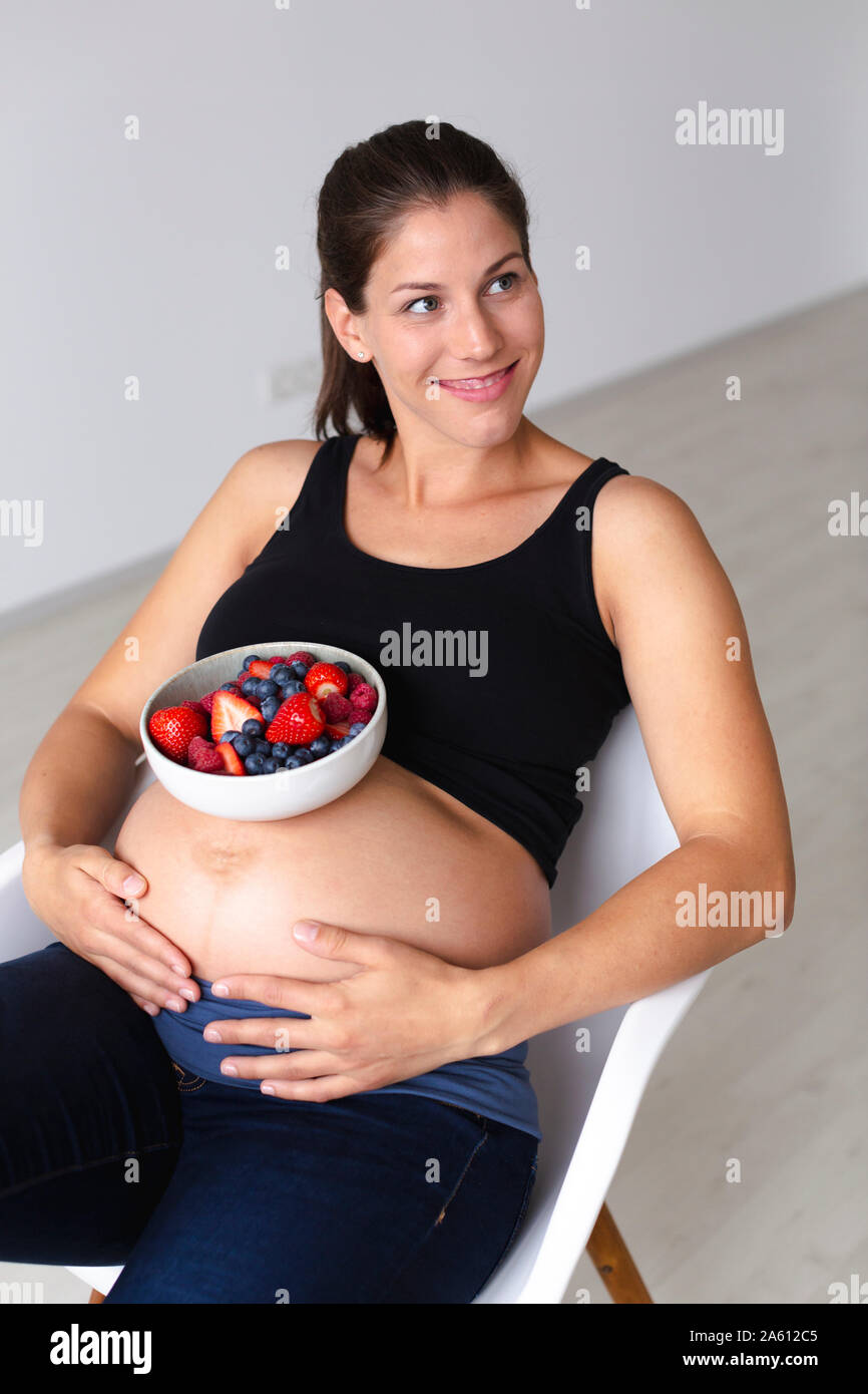 Junge schwangere Frau ist Essen verschiedene Arten von frischem Obst Stockfoto