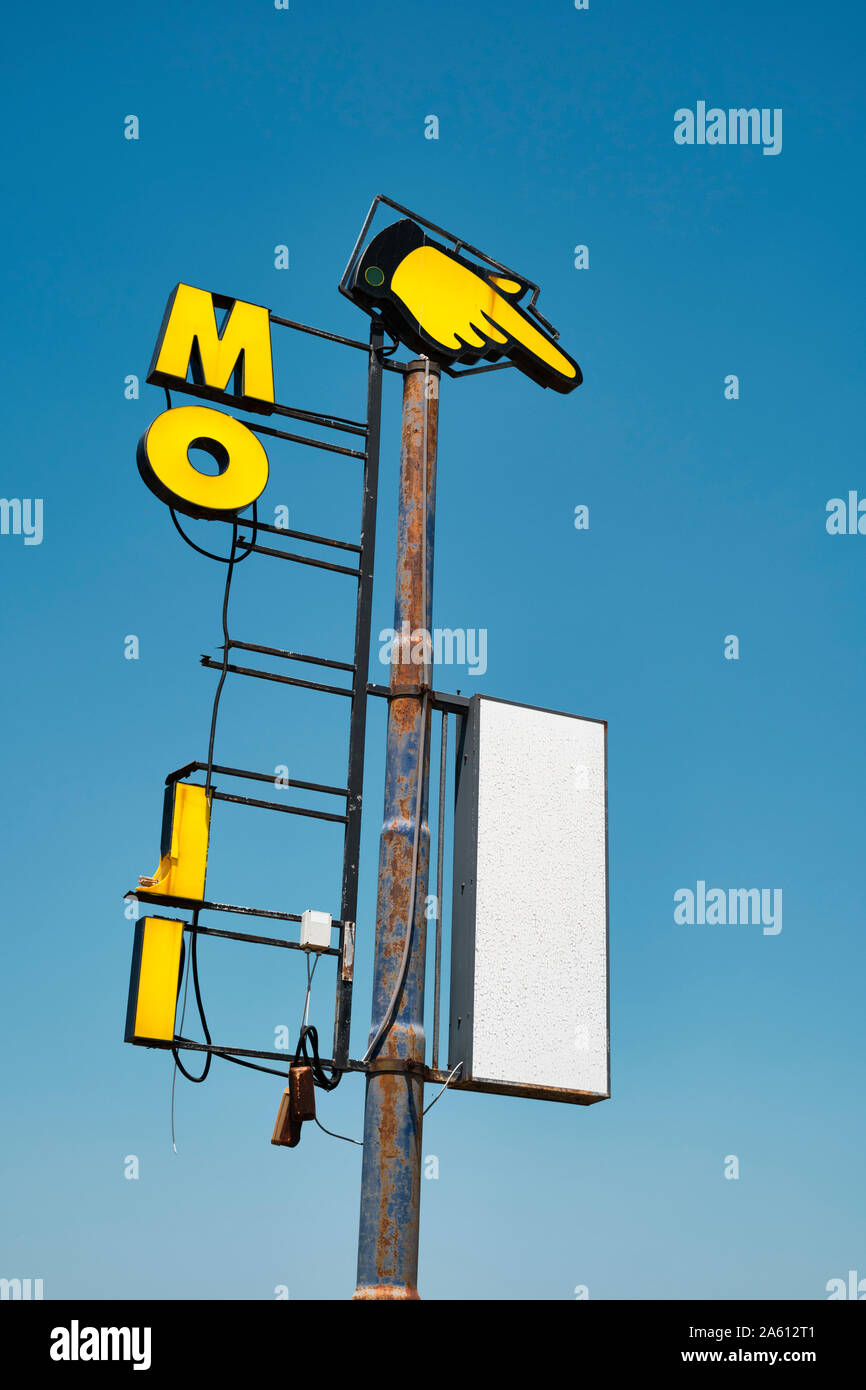 Ein altes gelbes Zeigefinger- und Handzeichen mit dem Buchstaben MO in einem tiefen blauen Himmel - Hand zeigt Richtung hier - baufällig altes Schild Stockfoto