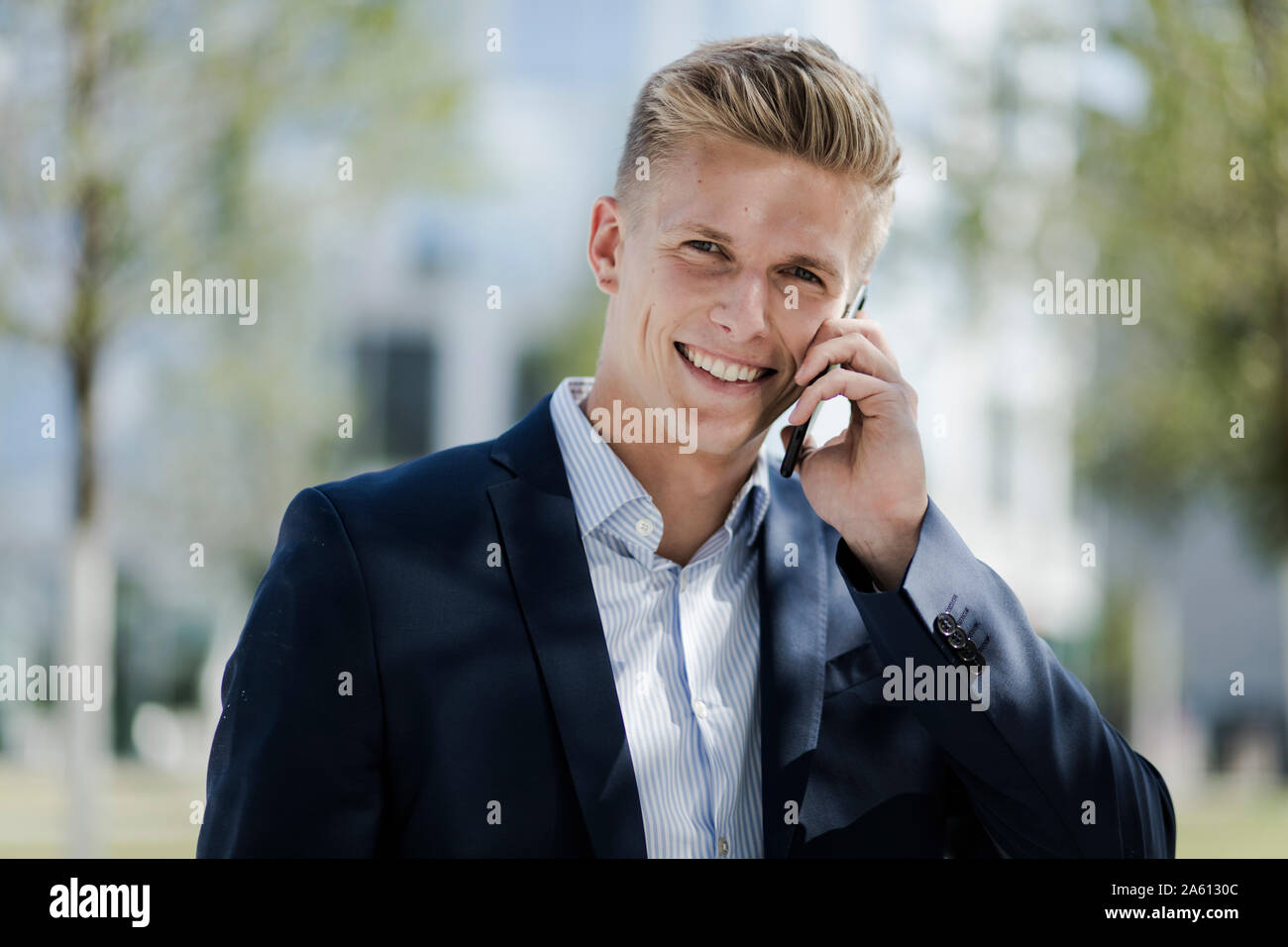 Portrait von lächelnden jungen Geschäftsmann mit Mobiltelefon Stockfoto