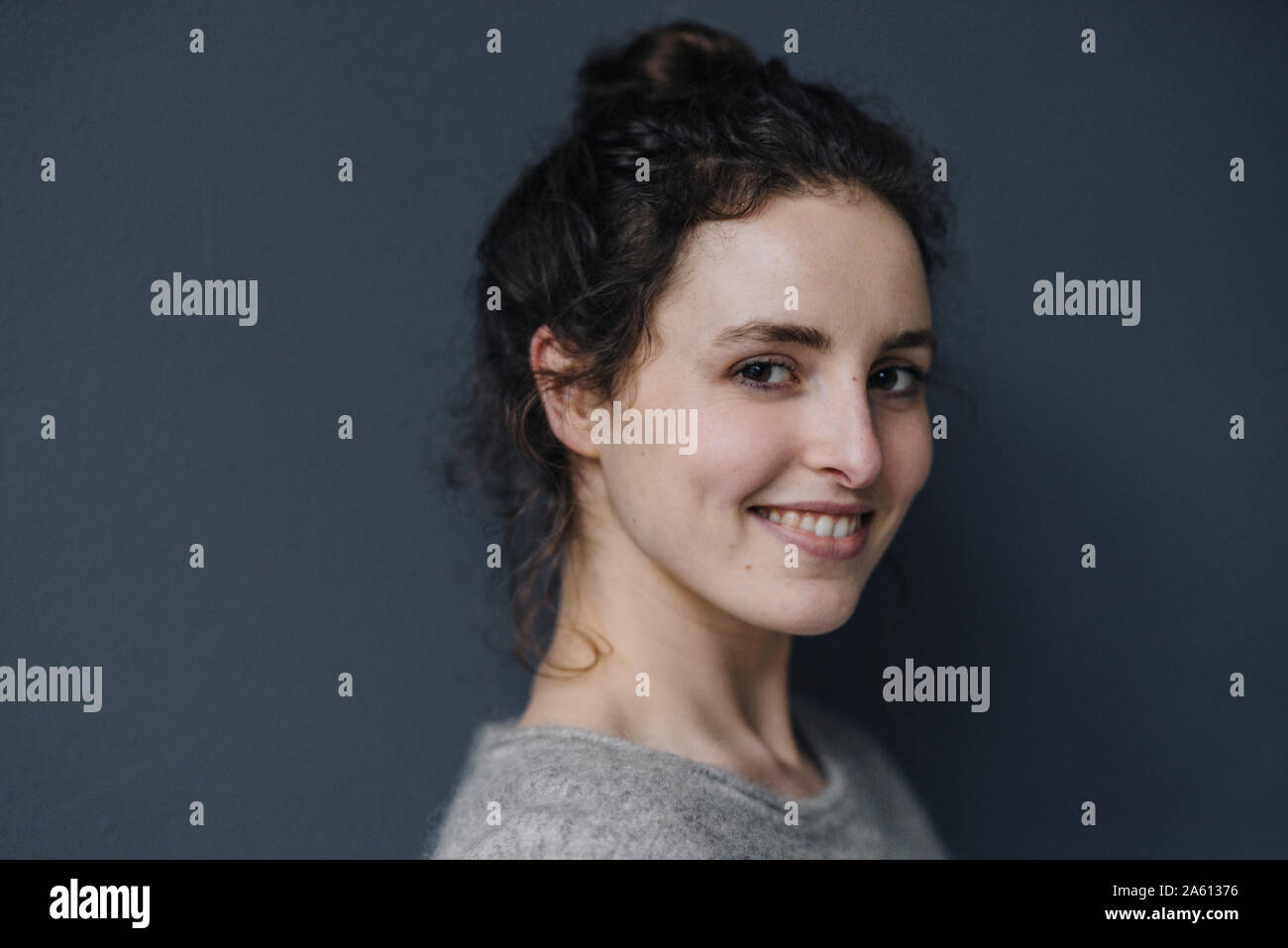 Portrait von lächelnden jungen Frau gegen grauer Hintergrund Stockfoto