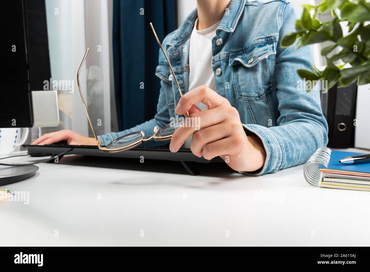 Frau, die in ihrem Heimbüro arbeiten, hipster Girl freie schriftlich auf dem Computer und halten Gläser in der Hand. Business Konzept Stockfoto