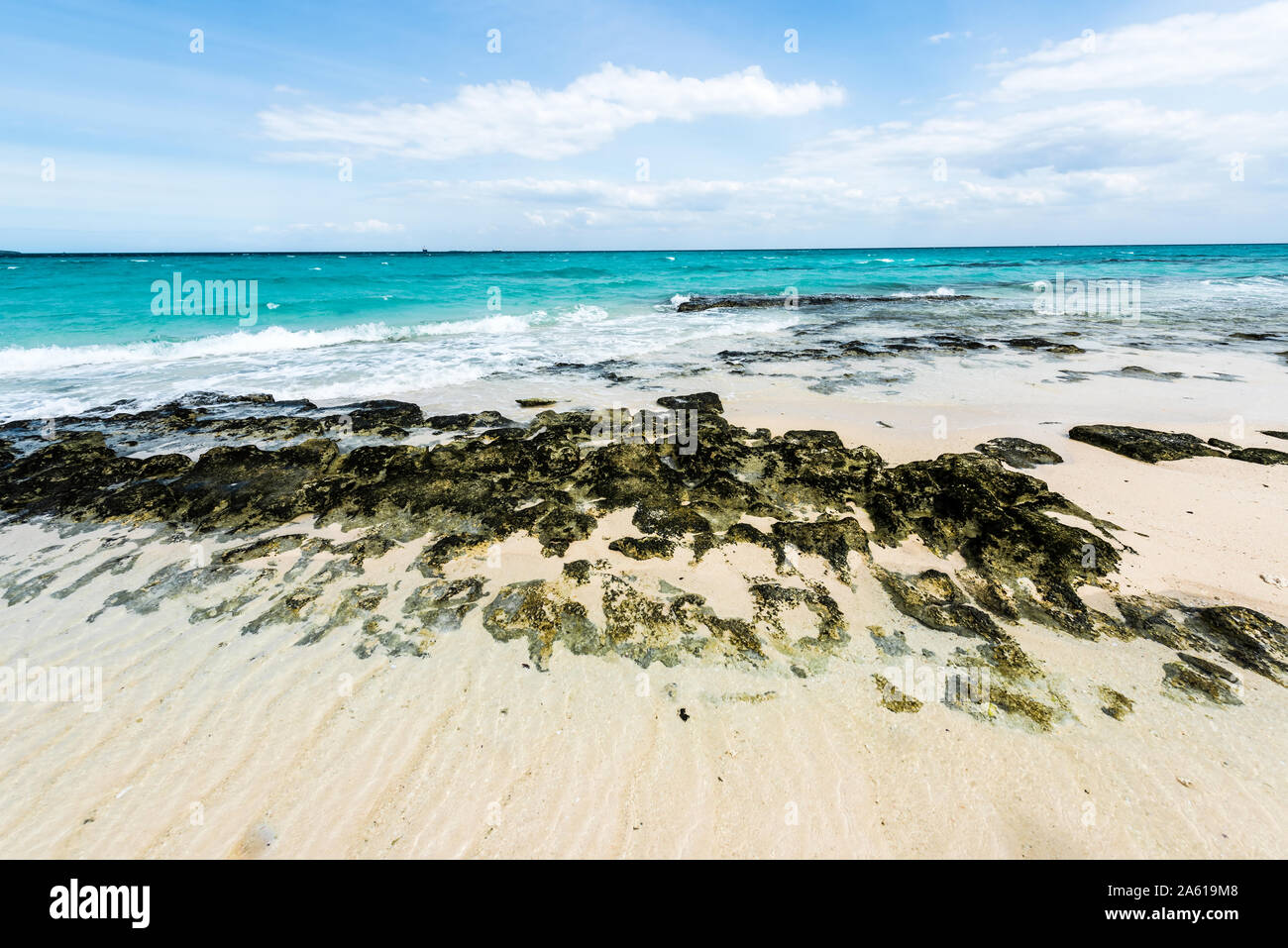 Steinige Küste und klaren türkisblauen Wasser des Ozeans mit blauen Himmel im Hintergrund Stockfoto