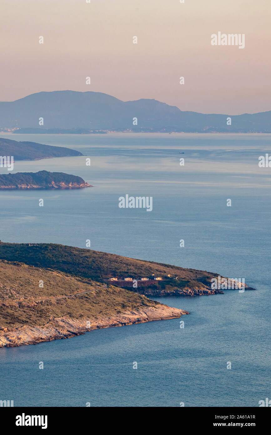 Goldene stunde Landschaft von Lekuresi Schloss, Saranda, Albanien mit Adria Küste, Clear Spring Sky mit abendlichen Dunst, Kerkira Insel in Griechenland im Hintergrund Stockfoto