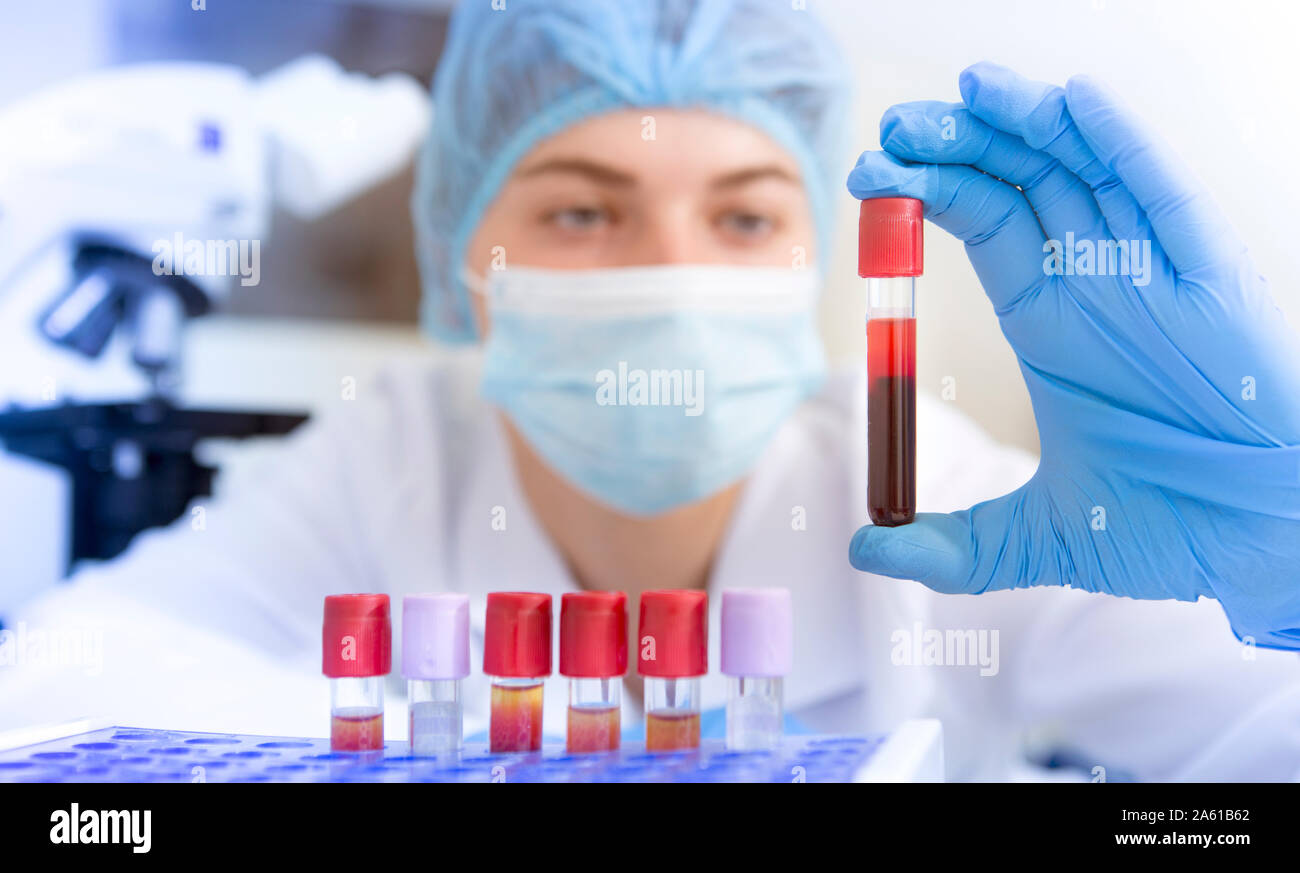 Junge attraktive Wissenschaftlerin holding Reagenzglas mit rotem Stoff Stockfoto