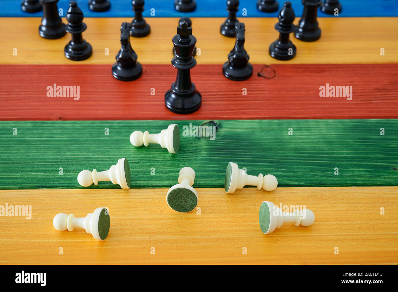 Schwarz Holz- Schachfiguren stand vor der gefallenen Weiß schach Schachfiguren in einem konzeptionellen Bild des Geschäfts macht. Stockfoto