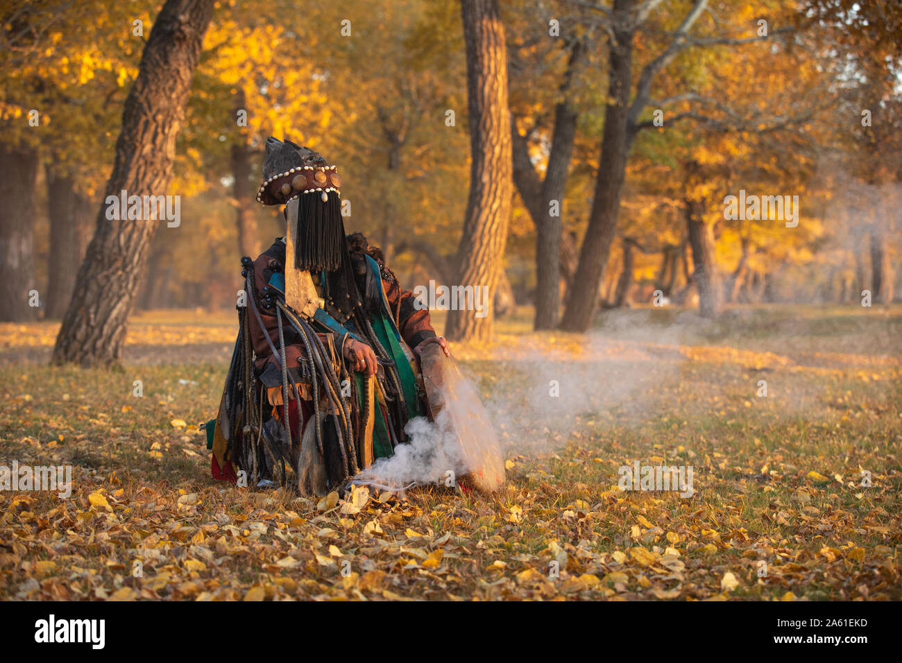 Traditioneller Mongolischer Schamane Durchführen einer traditionellen schamanistisches Ritual mit einer Trommel und Rauch in einem Wald im Herbst am Nachmittag. Ulaanbaatar, Mongo Stockfoto