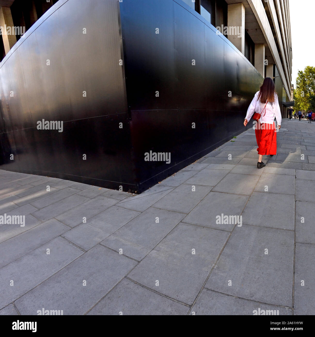 London, England, UK. Junge Frau in Weiß Top und Red Rock in the Strand Stockfoto