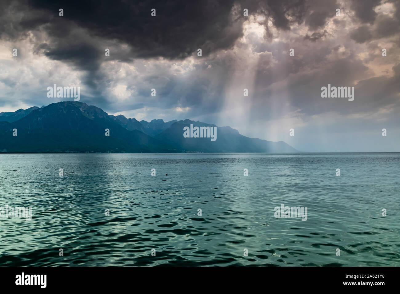 Landschaft der Alpen, Genfer See, dunkle Wolken mit Sonnenstrahlen vor dem Regen. Schuß vom Ufer des Sees in Montreux, Schweiz. Stockfoto