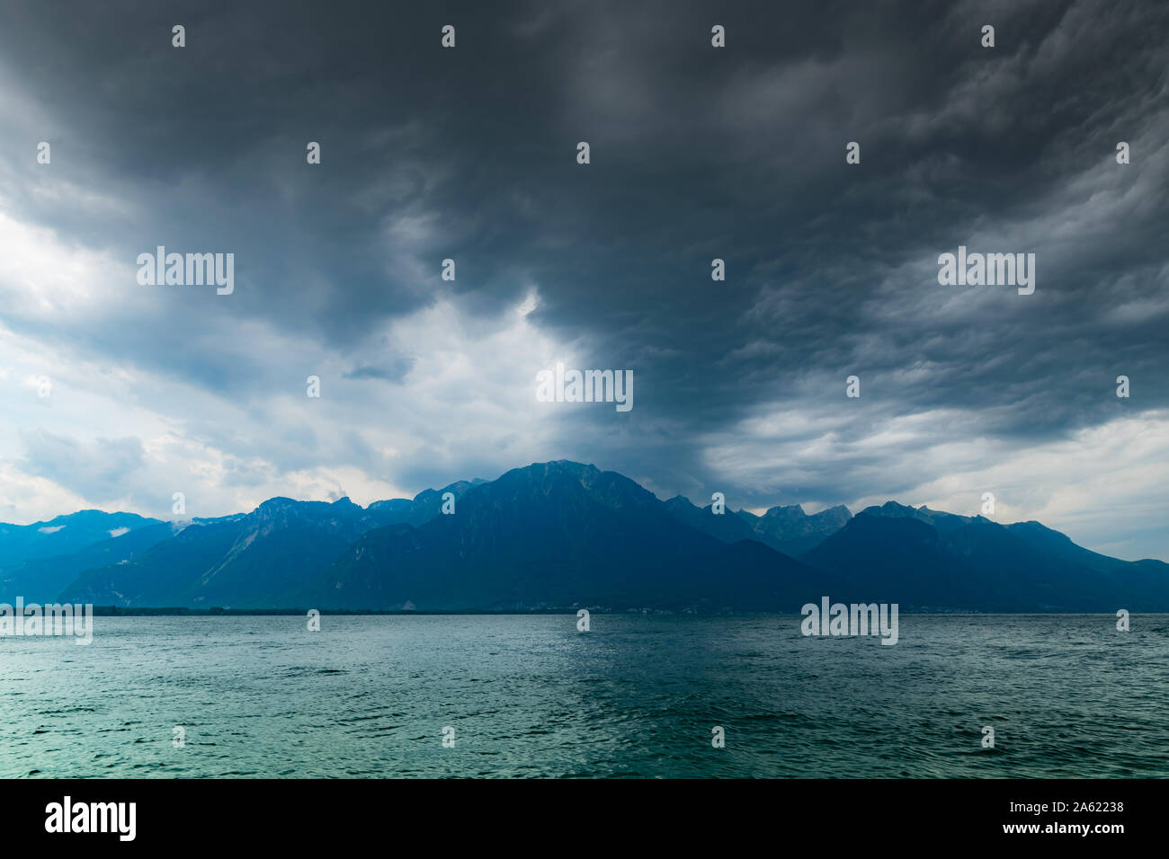 Blick auf die Alpen, den Genfer See und dunkle Regenwolken vor Regen. Schuß vom Ufer des Sees in Montreux, Schweiz. Stockfoto