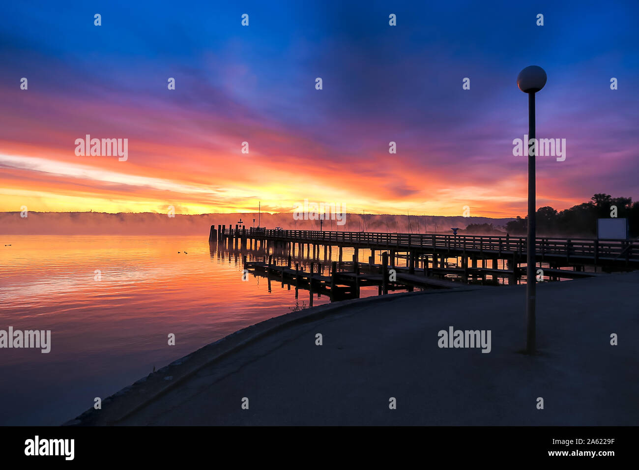 Ein buntes Spektakel bei Sonnenaufgang, Ammersee Bayern, mit Blick auf das östliche Ufer mit Kloster Andechs Stockfoto