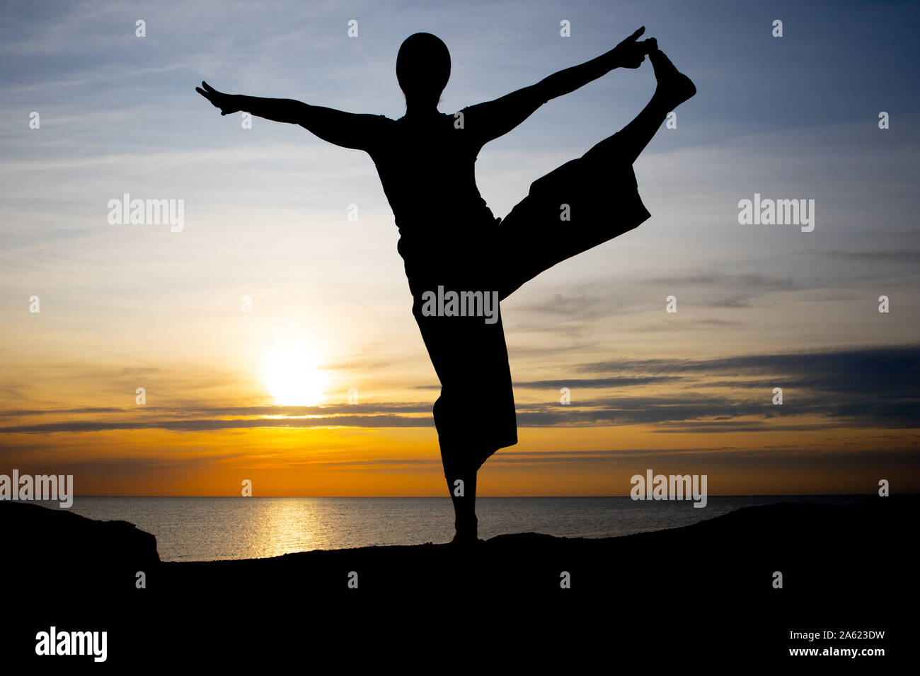 Silhouette einer Frau bei Sonnenuntergang, Yoga Position gegen die untergehende Sonne auf der Insel Bornholm, Dänemark, Yoga bei Sonnenuntergang auf der Insel Stockfoto