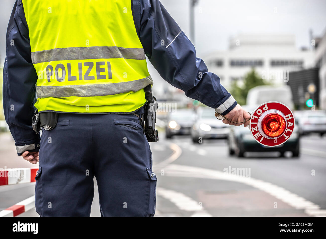 Polizist mit einer gelben Warnweste und ein Stoppen der Pfanne bei einer Verkehrskontrolle, Stockfoto