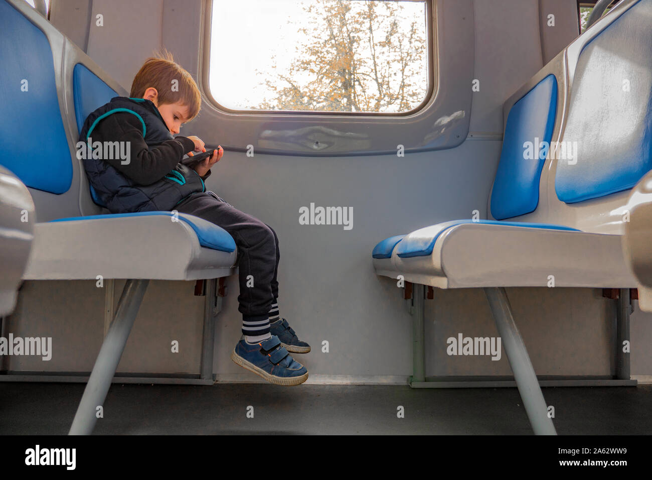 Junge mit Handy im Zug sitzen. Kinder und Technologien. Junge Junge, die Spiel am Telefon während der Sitzung in Zug. Qualität der Internetverbindung. Junge Reisende Reisen mit elektronischen Karte Stockfoto