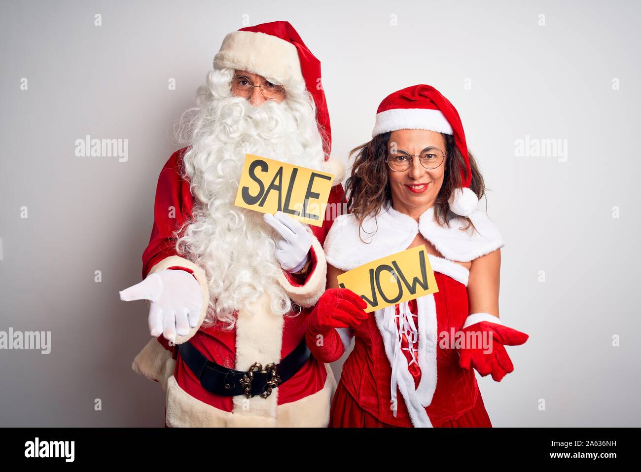 Paar Tragen santa Kostüm Holding wow und Verkauf Banner über isoliert weißer Hintergrund lächelt Fröhlich bietet Palm hand Hilfeleistung und acce Stockfoto