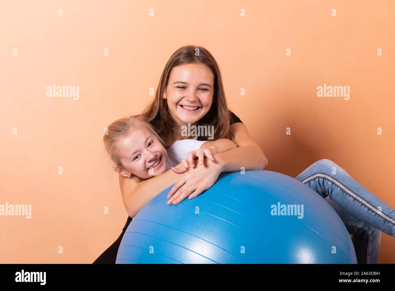 Mädchen auf einem Gymnastikball, auf einem hellen orange hinterlegt. Stockfoto