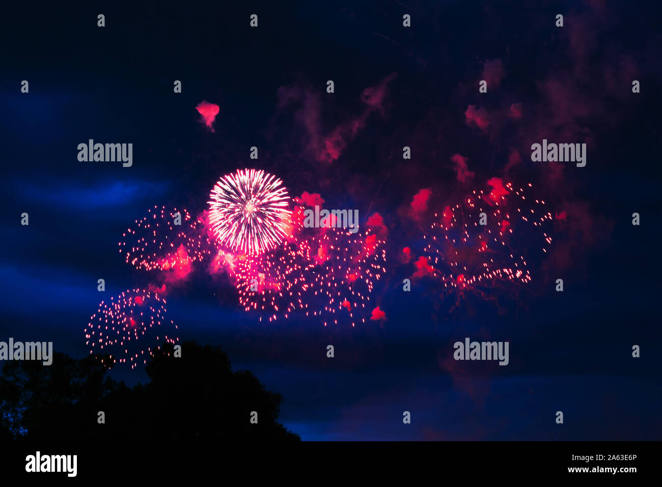 Preiswertes Feuerwerk über der Stadt rot, rosa und weiß. Hell und glänzend. Für jeden Zweck. Feier Konzept. Stockfoto