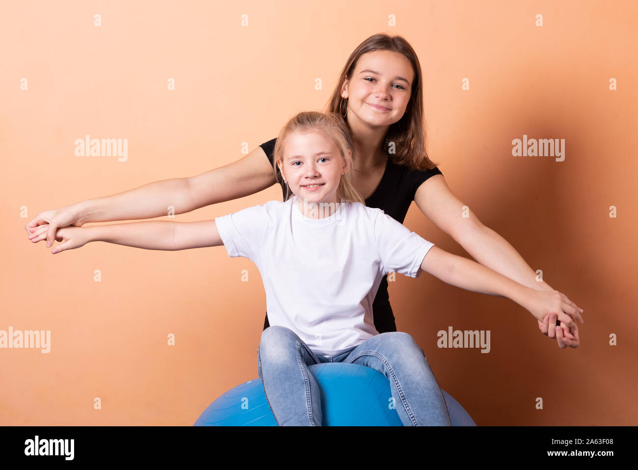 Mädchen auf einem Gymnastikball, auf einem hellen orange hinterlegt. Stockfoto