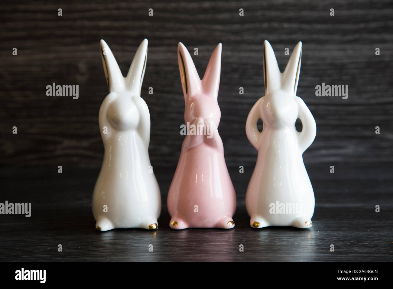 Keramische Ziergegenstände Kaninchen Anzeigen sehen und nichts sagen, hören kein Übel. Rosa und Weiß, Gold Ohren und Füße. Nützlich für Ostern. 3 Affen Stockfoto