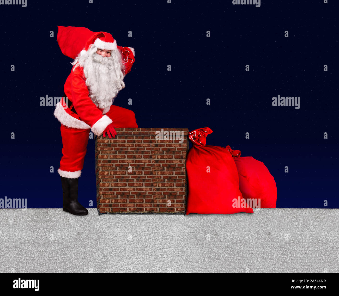 Weihnachtsmann mit Sack der Weihnachtsgeschenke treten in einen Schornstein auf verschneiten Dach. Stockfoto