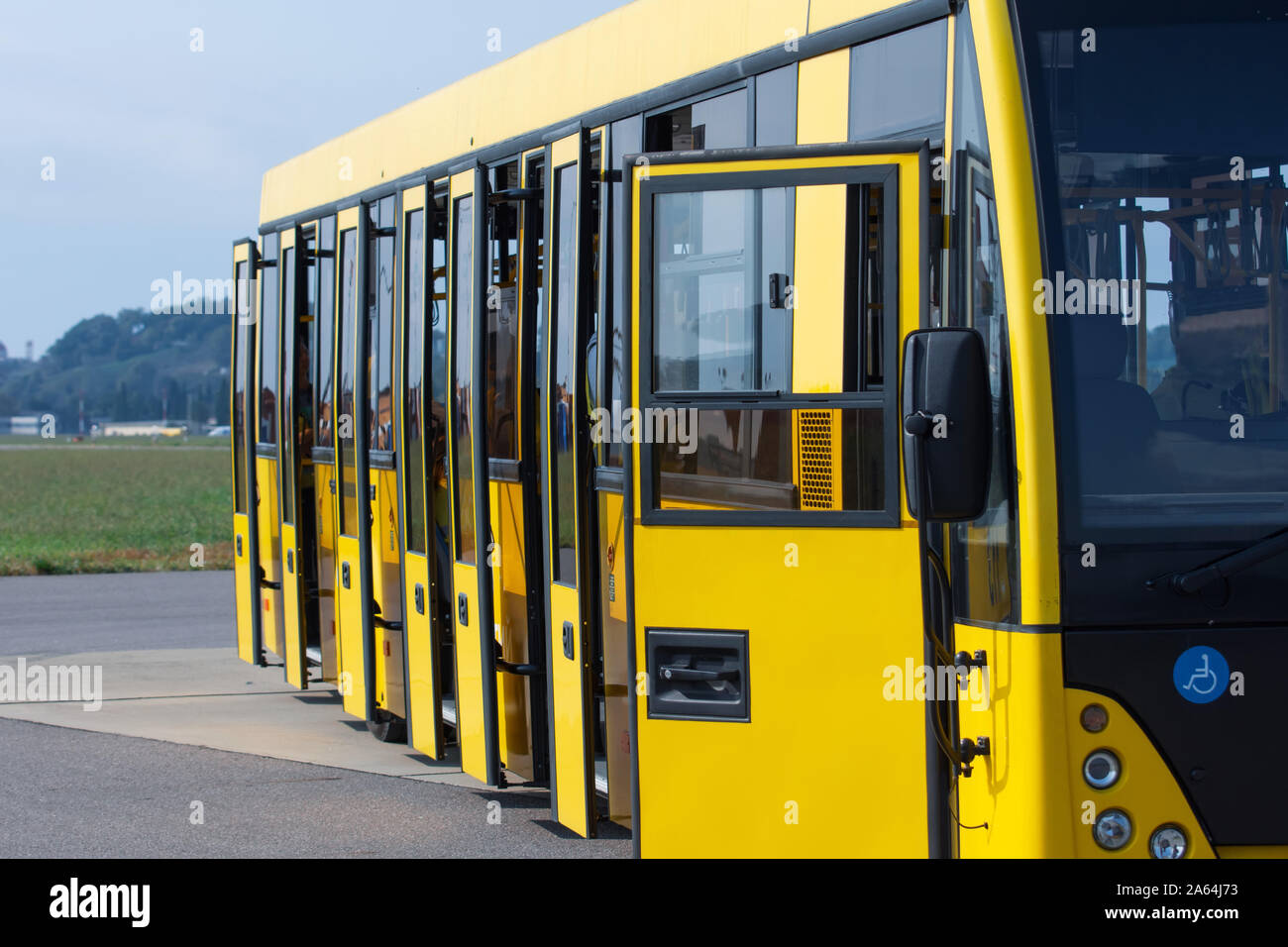 Gelbe Busunternehmen mit offenen Türen warten auf Passagiere mit dem Flugzeug am Flughafen zu transportieren Stockfoto