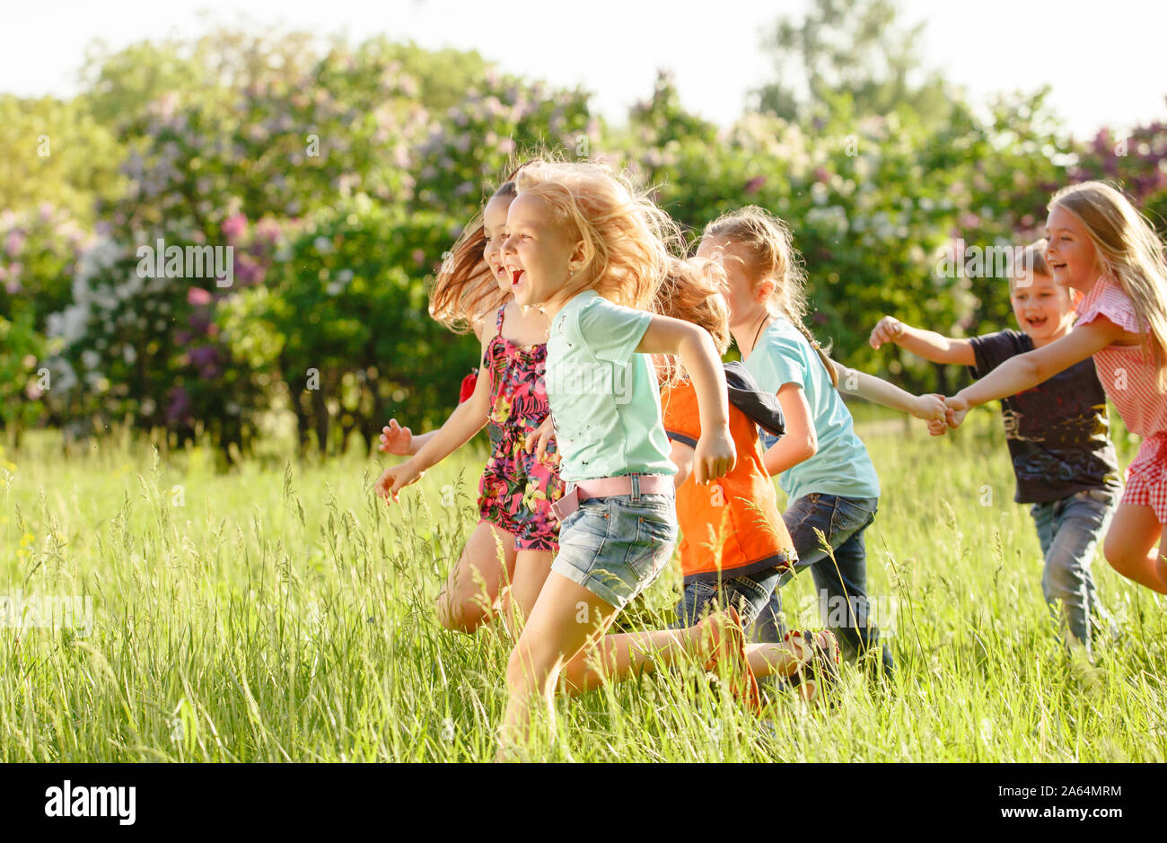 Eine Gruppe von glückliche Kinder von Jungen und Mädchen laufen im Park auf der Wiese an einem sonnigen Sommertag. Das Konzept der ethnischen Freundschaft, Frieden, Freundlichkeit, ch Stockfoto