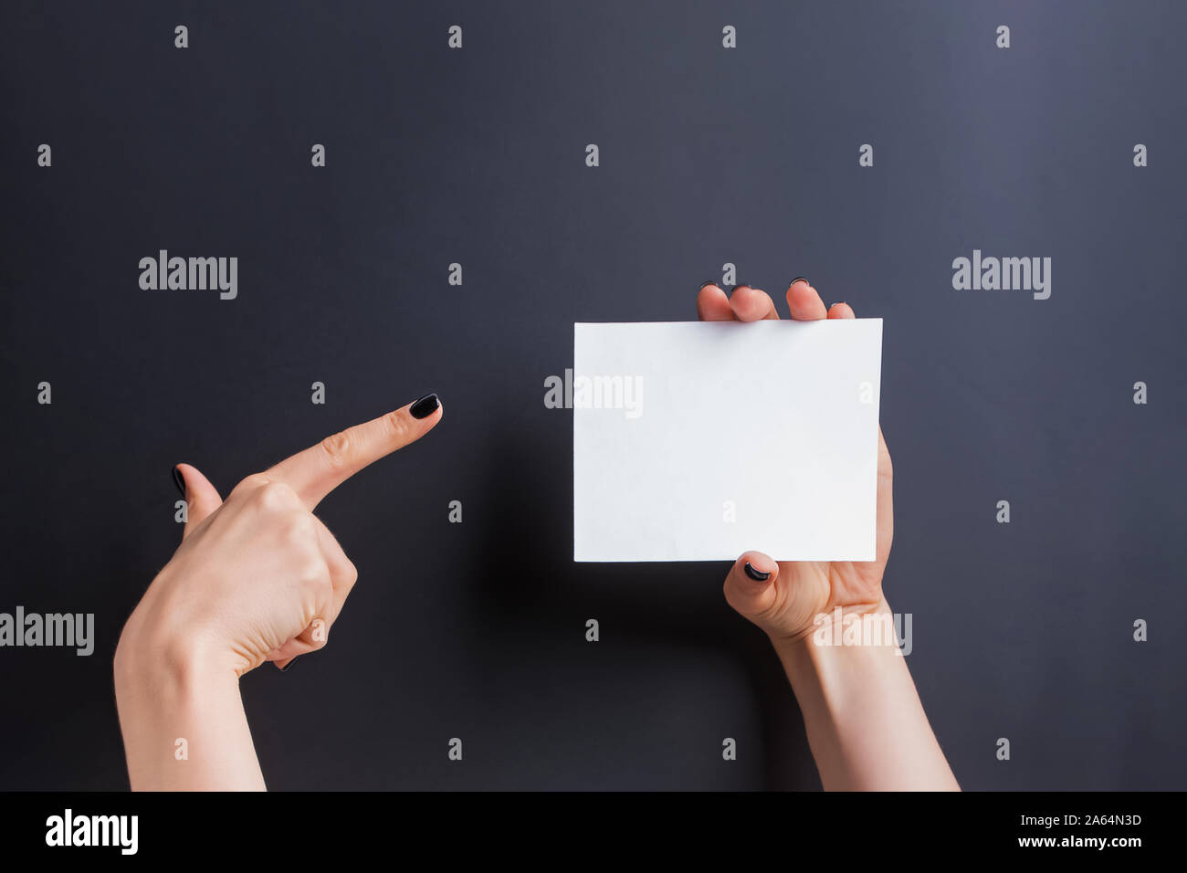 Woman's Hände halten eine leere Karte mit einer Hand und zeigen Sie mit dem Finger der anderen. Stockfoto