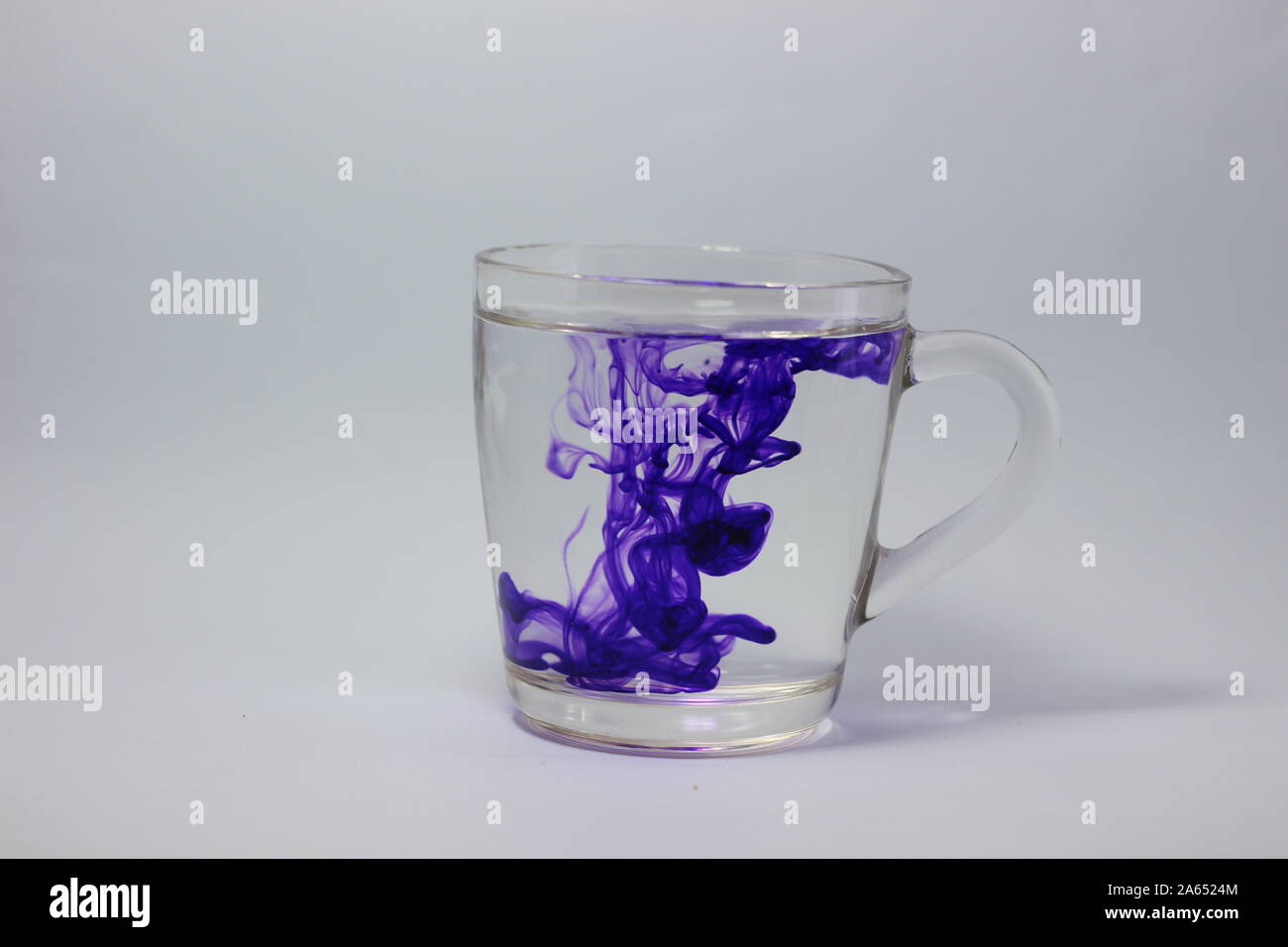 Glas auf weißem Hintergrund mit blauen Farbe Farben innen Stockfoto