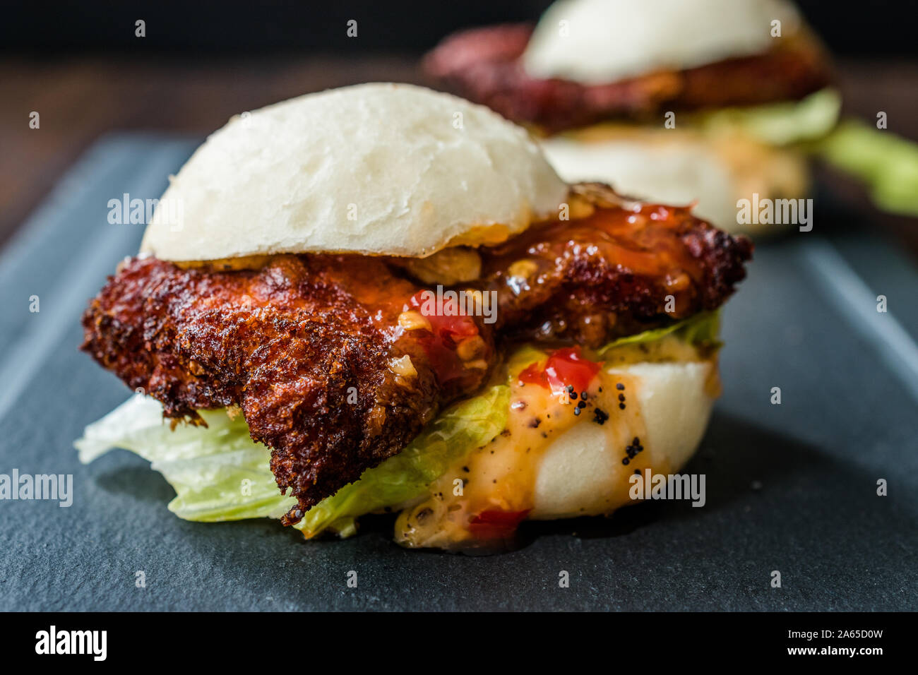 Gua Bao Burger mit knusprigen Hähnchen und Red Hot Chilli Relish Sauce Brötchen. Fast Food. Stockfoto