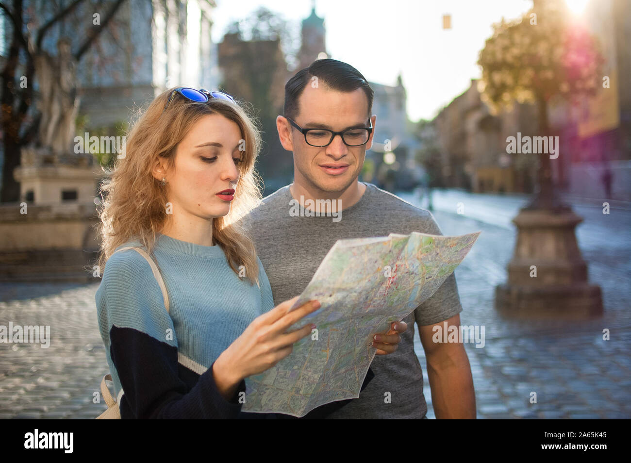 Touristen auf der Suche nach der Karte auf Papier und auf der Suche nach Richtung früh morgens auf leeren alten Platz irgendwo in Europa Stockfoto