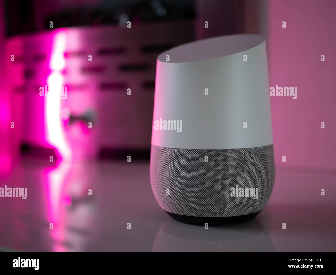 Smart Home Lautsprecher Assistant auf Kamin mit LED-farbiges Umgebungslicht - Fuschia Stockfoto