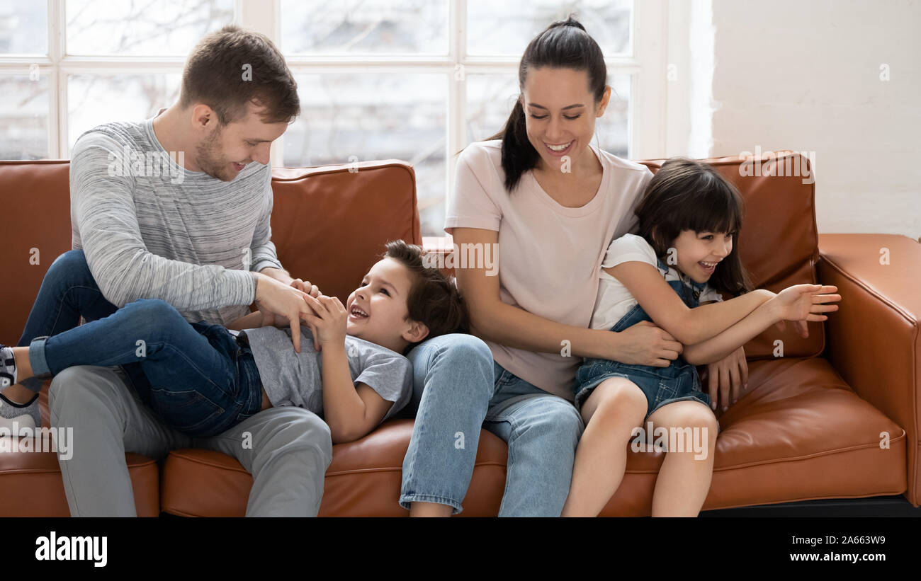 Glückliche Eltern sitzen auf der Couch und spielt mit den Kindern. Stockfoto