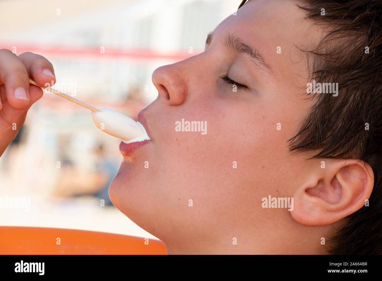 Eine Nahaufnahme Foto eines Jungen essen eine Weiße Vanille Eis am Stiel Stockfoto