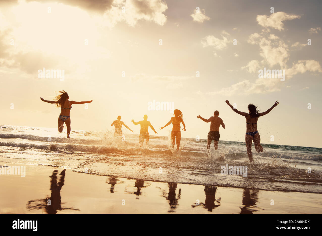 Silhouetten der glückliche Freunde läuft bei Sonnenuntergang am Strand. Strandferien Konzept Stockfoto