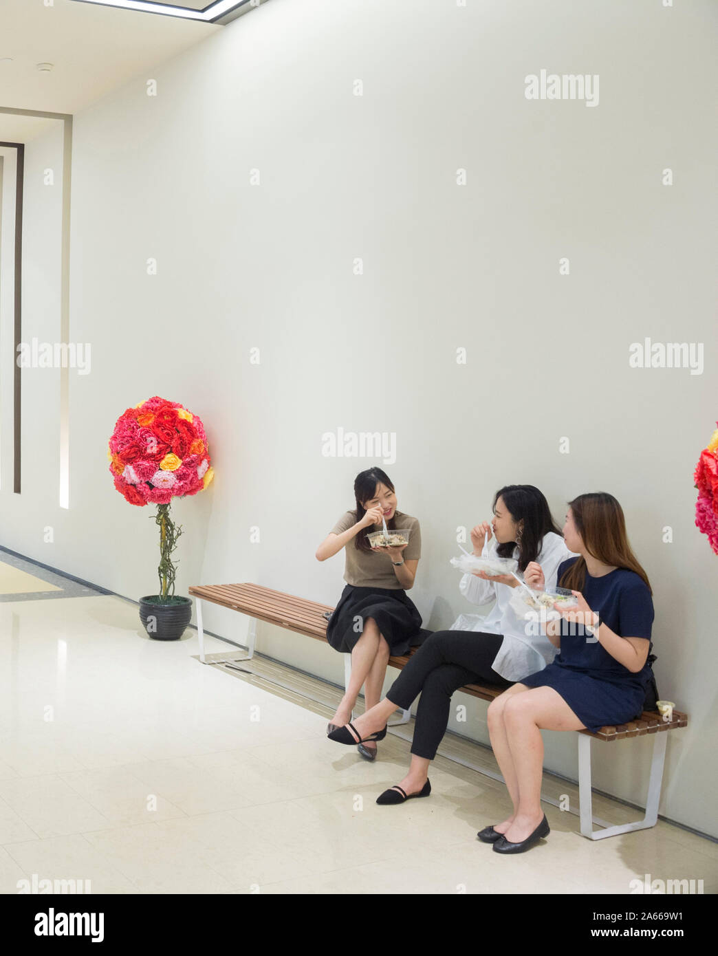 Singapur - Februar 16, 2017: Frauen mit einem Mittagessen auf dem beanch innen modernes Einkaufszentrum in Singapur. Stockfoto