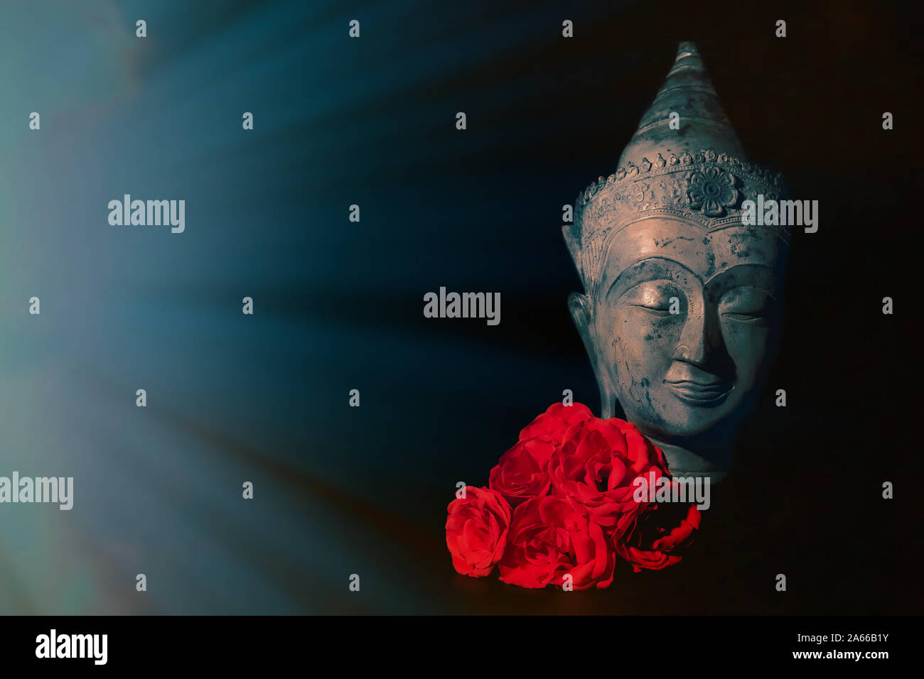 Frieden und Liebe. Traditionelle Meditation Buddha Kopf mit roten Rosen isoliert auf schwarzen Hintergrund mit Copyspace. Wunderschönes friedliches Bild. Ruhigen Buddhistischen Stockfoto